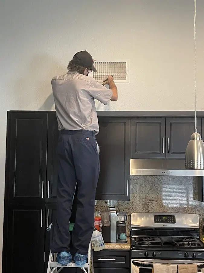 Technician inspecting an air vent during HVAC service in Tustin